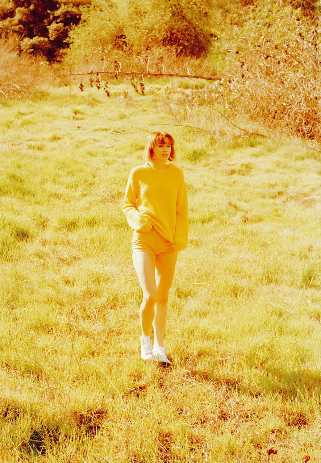 Nikki standing middle of the grass field wearing yellow outfit