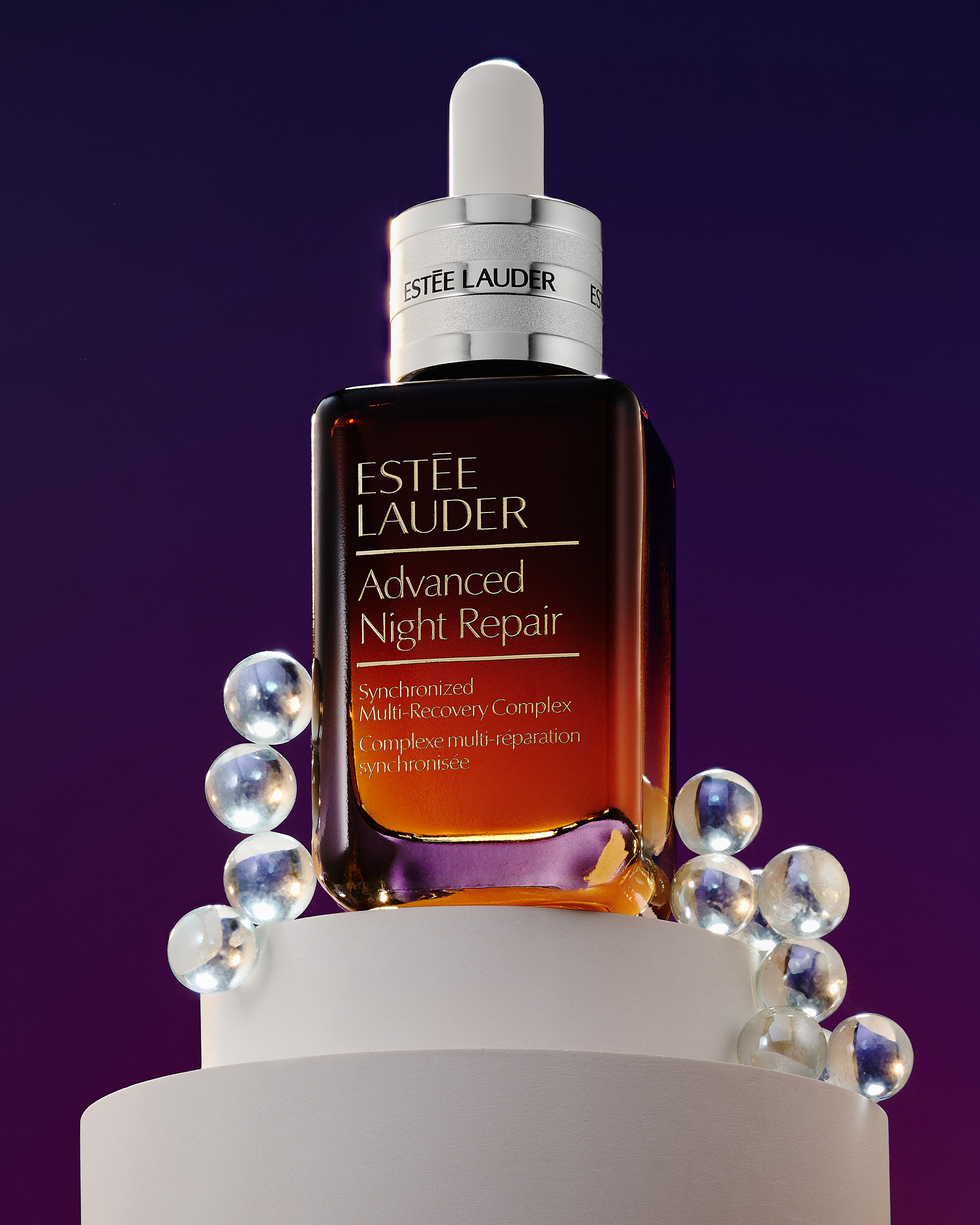 Estee Lauder on a white podium with clear crystal orbs