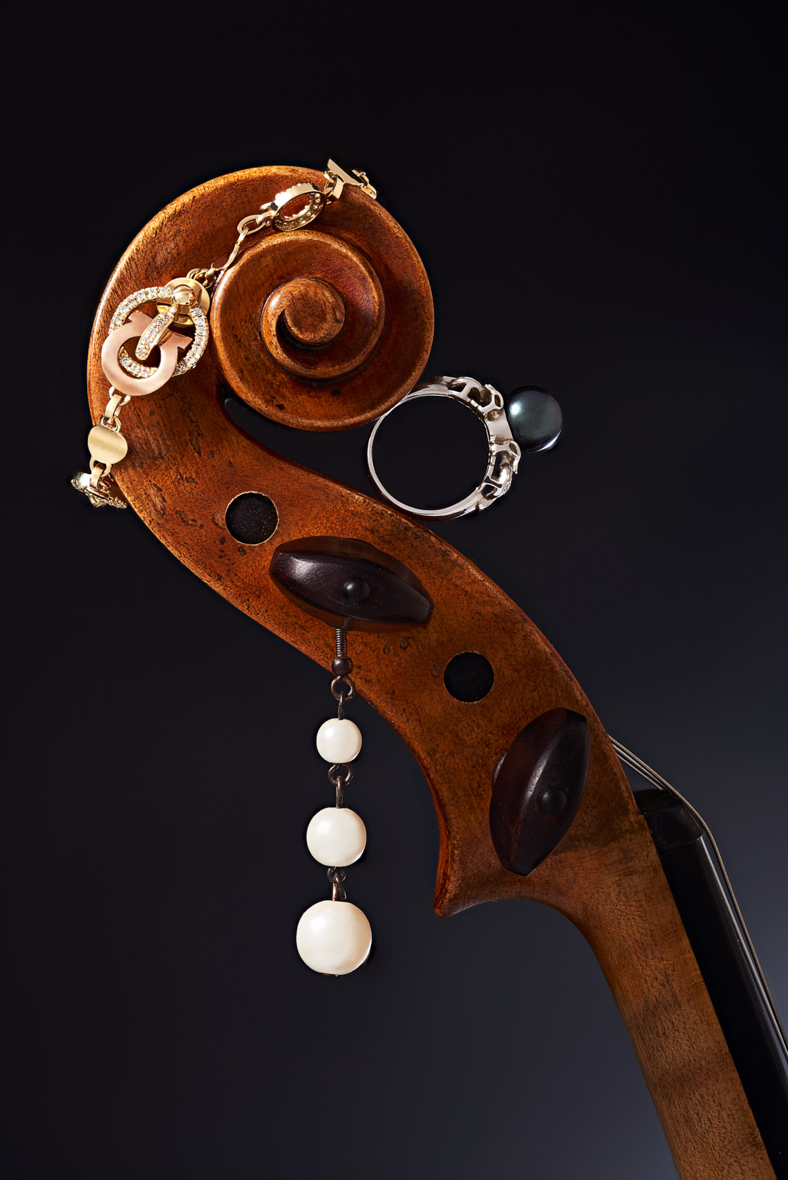 jewelry editorial on a violin head with pearl earring, ring, and pendant