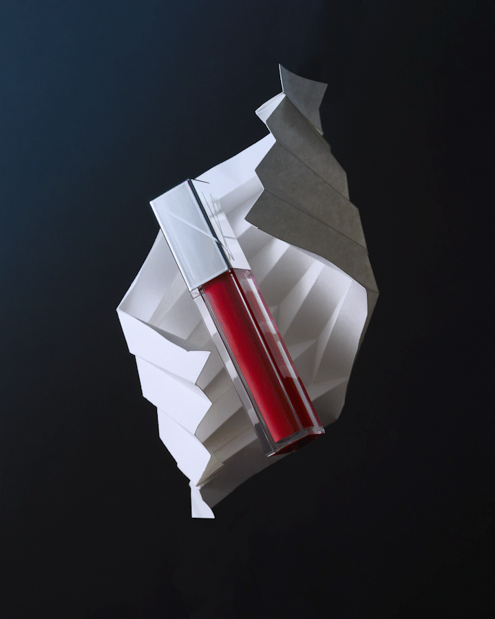 NARS Lipgloss rotating in the air with paper folds while changing color