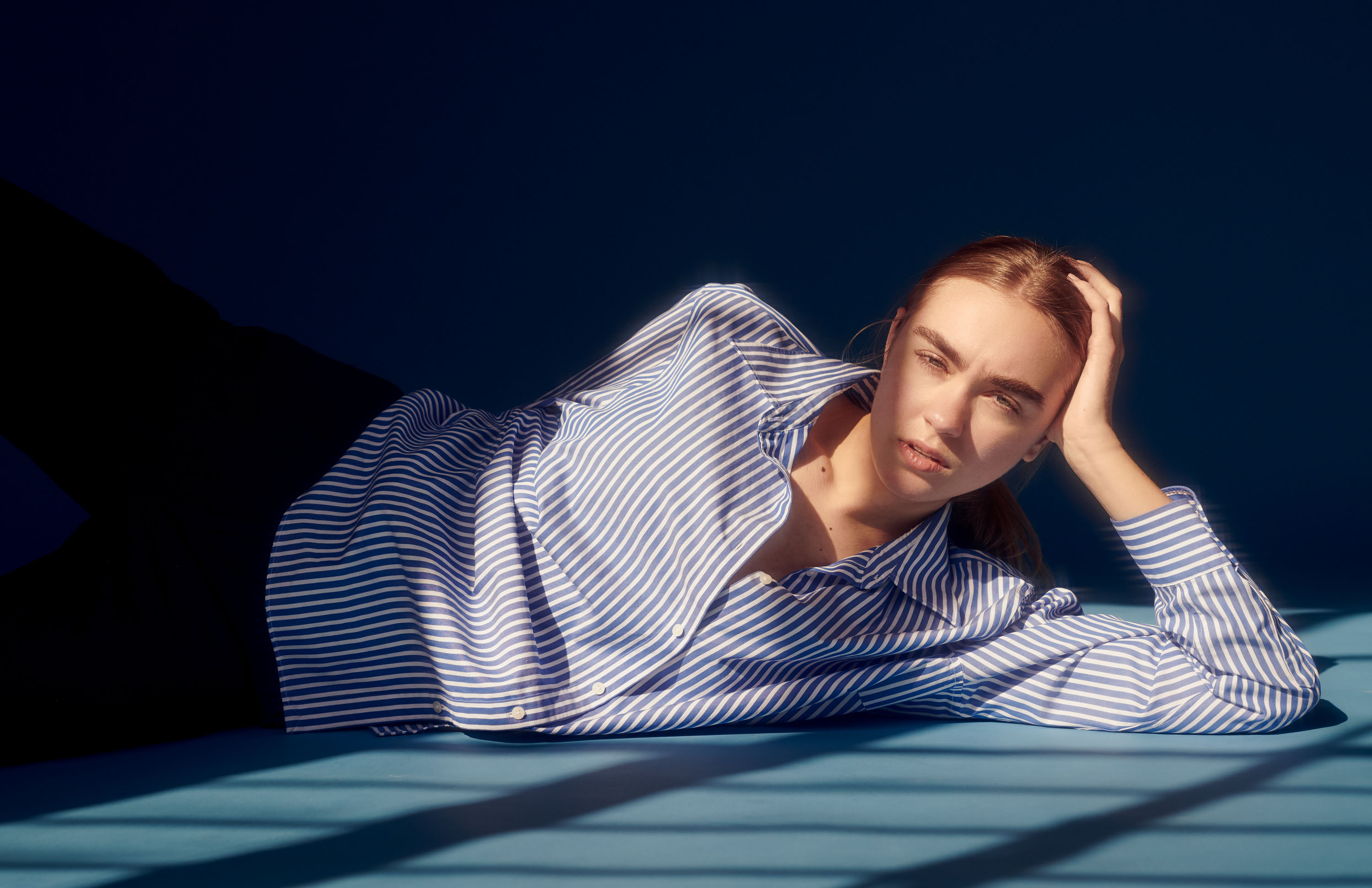 Model Rachel Hemstreet from Genetic Model laying on a blue sheet with window light on her face