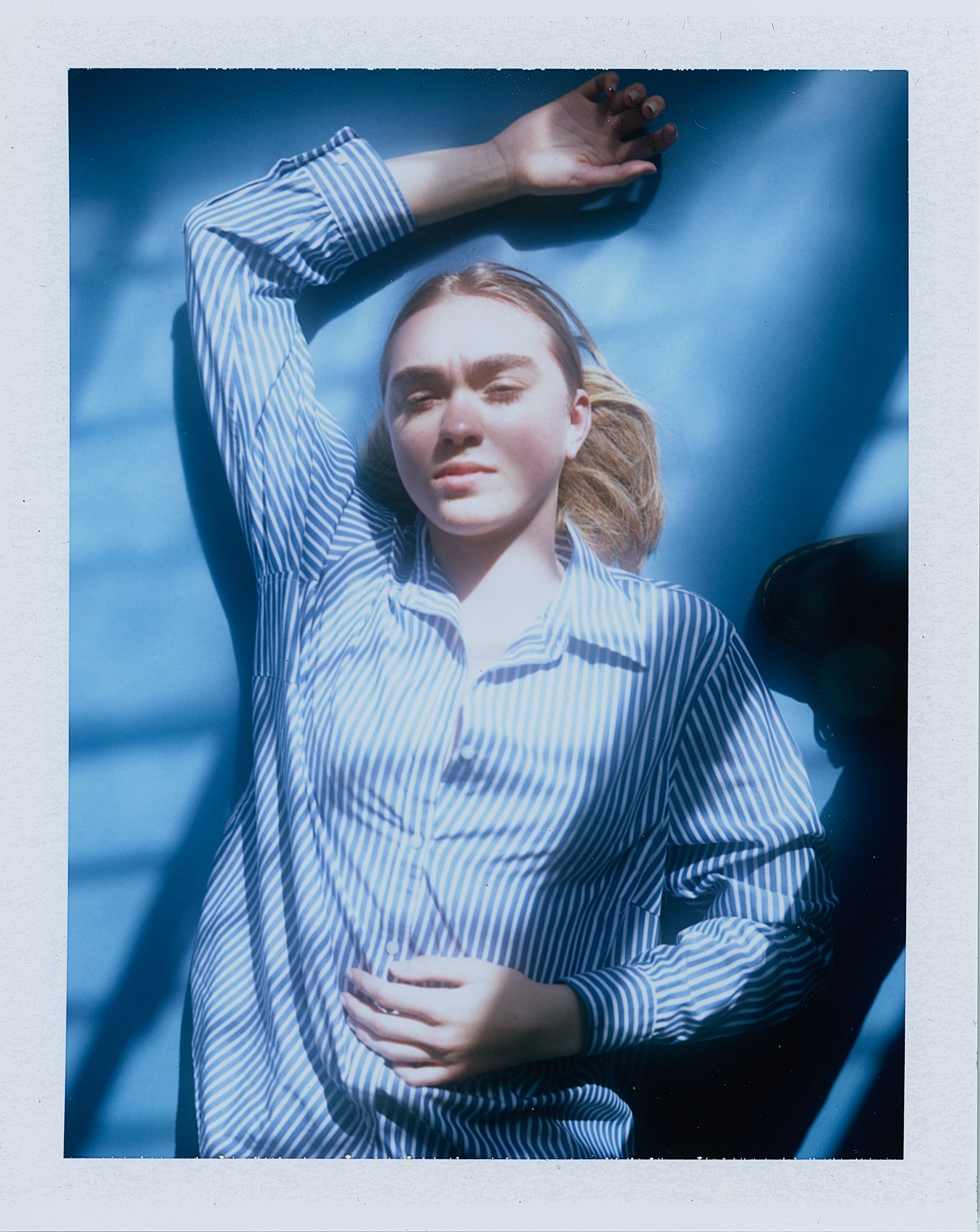 Polaroid shot of Rachel Hemstreet laying on a blue background 