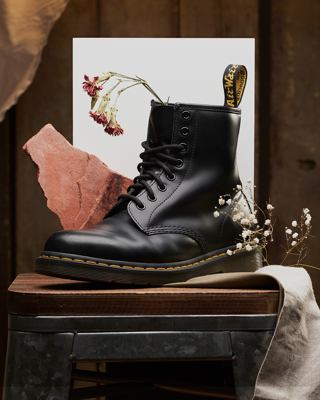 Dr.Marten Boot on a Wooden stool with red rock, dried flower, and paper 